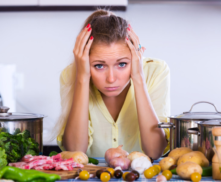 Frustrated woman looking at dinner ingredients with sad face
